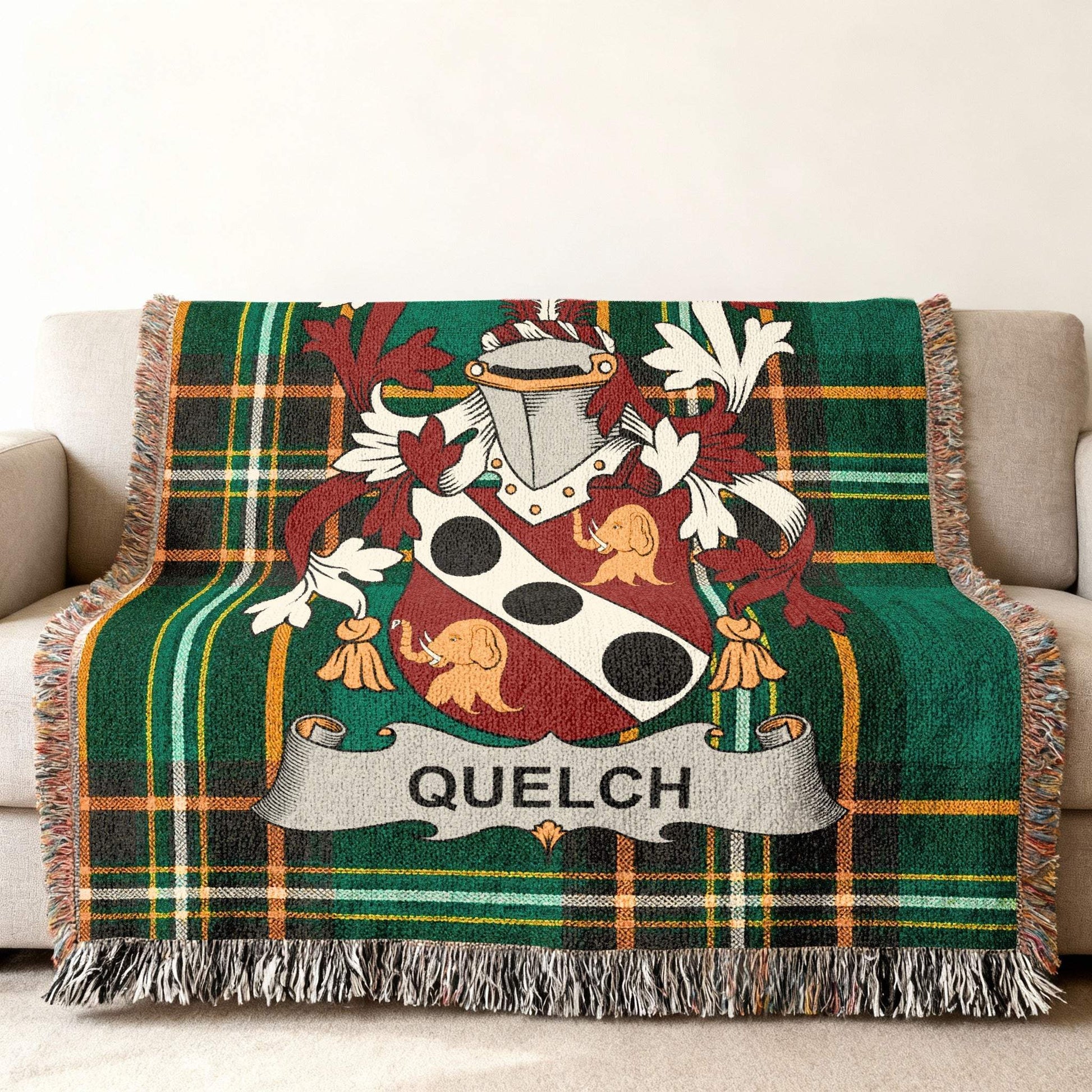 Green plaid throw blanket with a coat of arms and the name QUELCH.