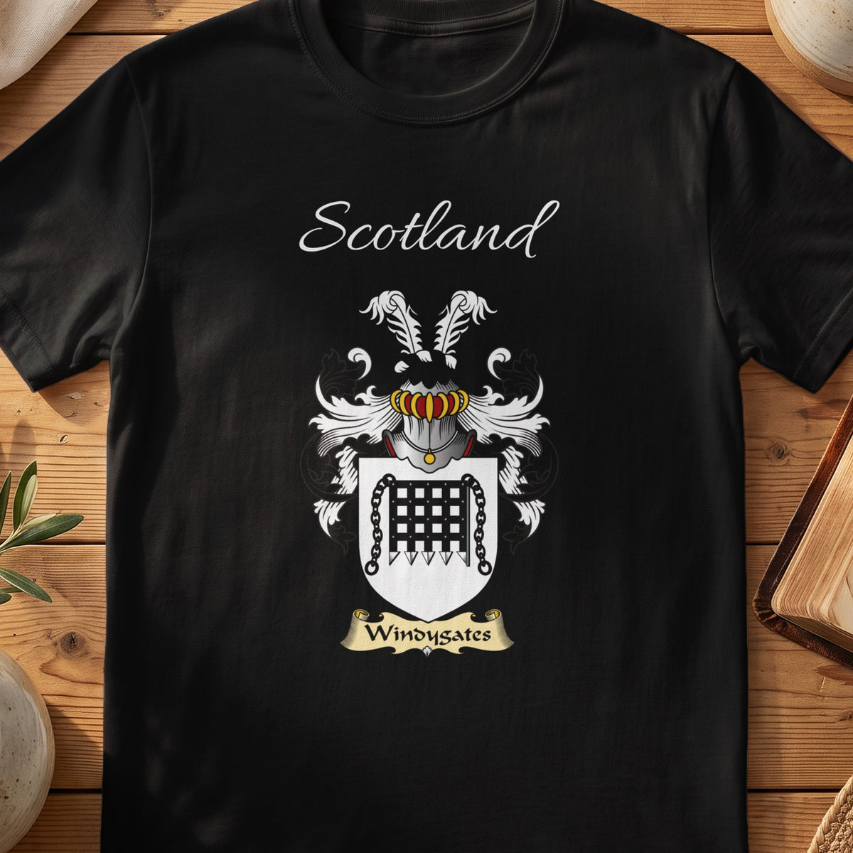 Black Windygates Scottish family crest T-shirt laid flat, showing “Scotland” above a black-and-silver shield featuring a gate-like emblem.