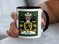 Lloyd Welsh coat of arms accent mug with black handle held in hand on Welsh National Tartan
