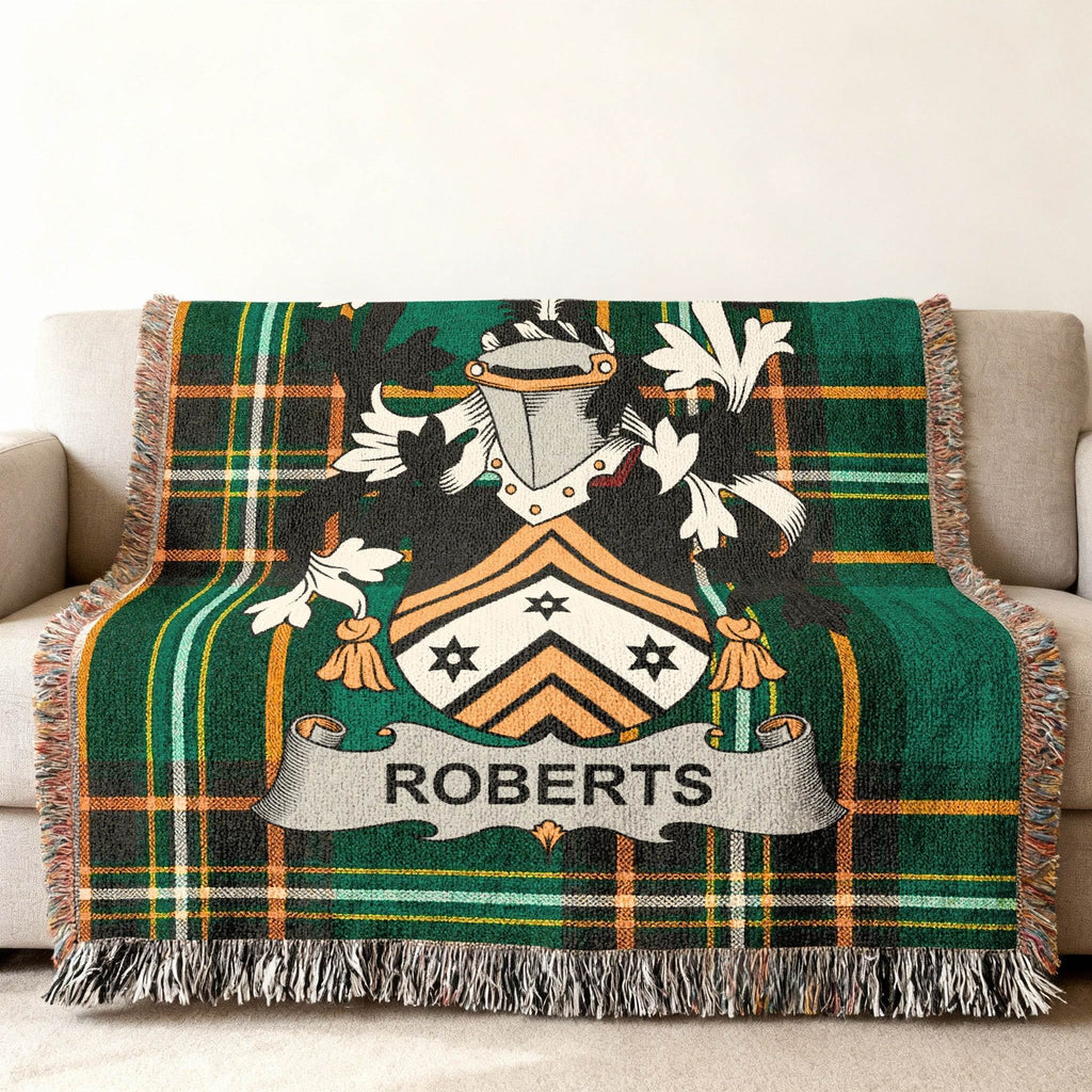Green tartan blanket with Roberts family crest on a sofa.