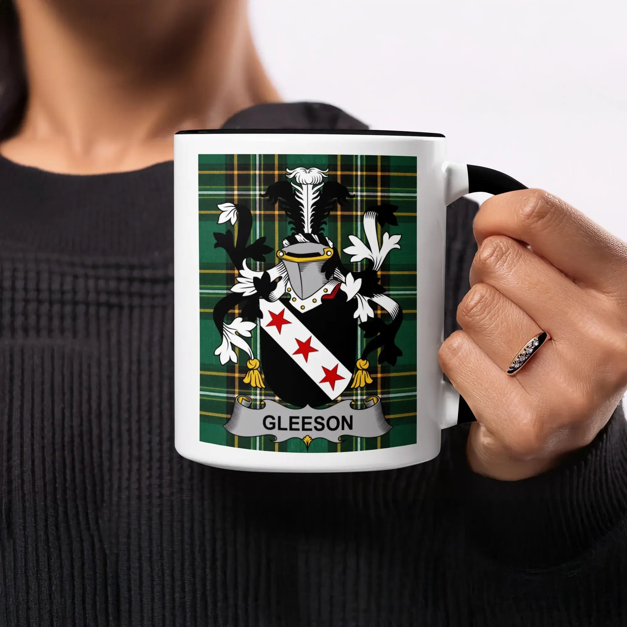 Gleeson family crest on a black and white mug held by a person.