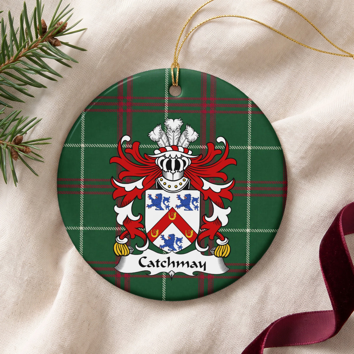 Catchmay ornament on cream fabric with gold string, evergreen and burgundy ribbon; a red chevron bearing three gold horseshoes between three blue lions on a white shield on Welsh national tartan.