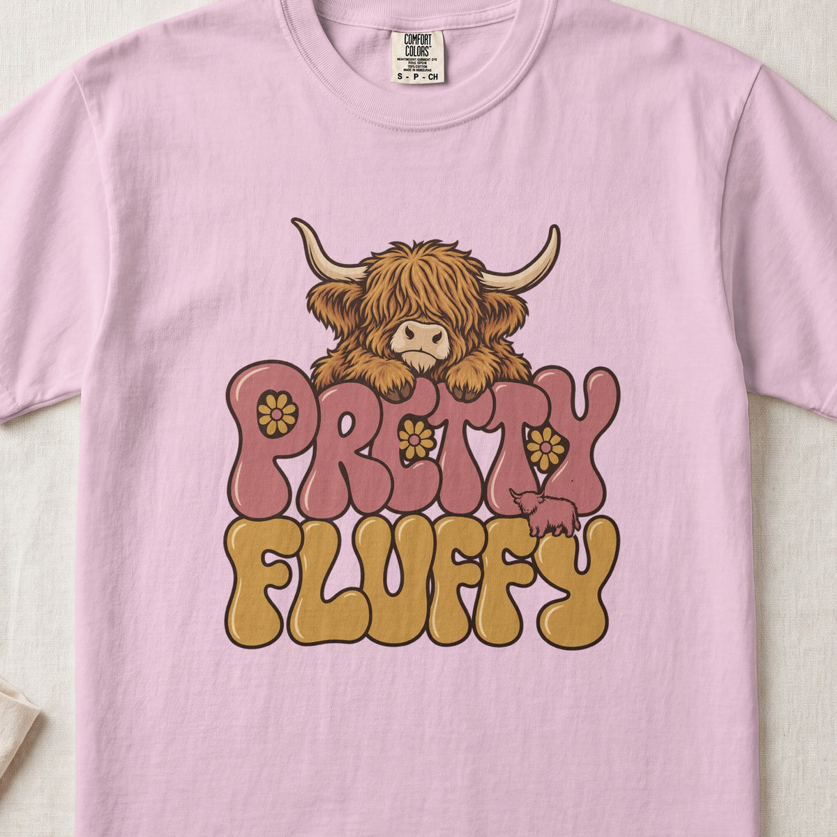 Pretty Fluffy Highland cow design on a Blossom Comfort Colors 1717 T-shirt, flat lay