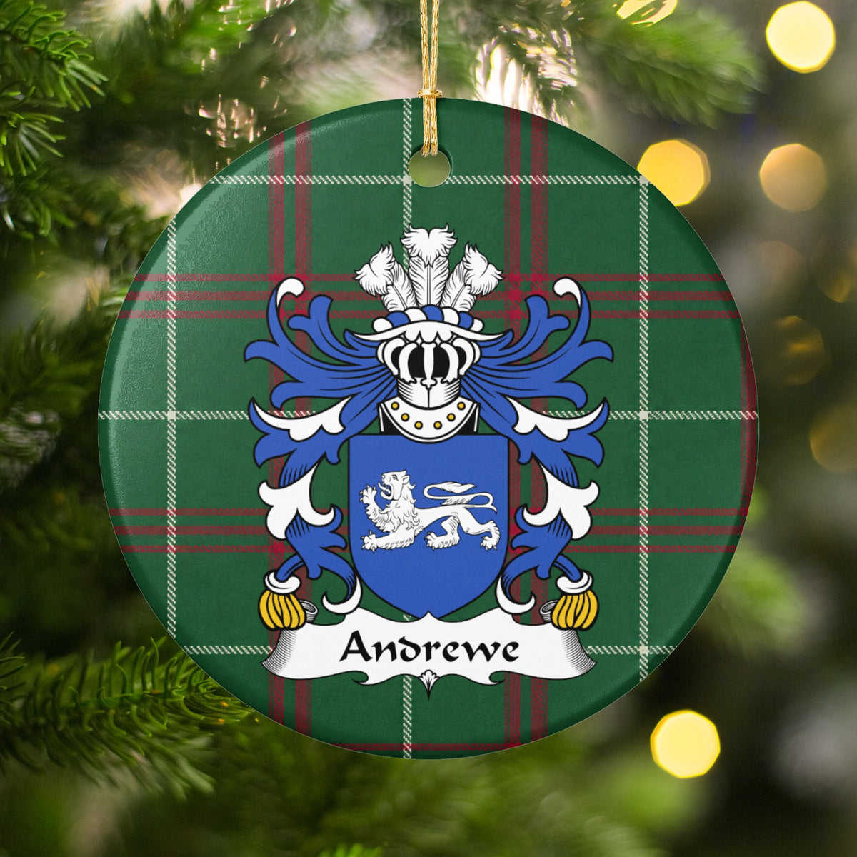 Andrewe family crest and surname on a round Welsh national tartan ornament, hanging by a gold cord among Christmas tree branches and warm golden lights.