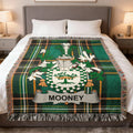 Tartan blanket with Mooney coat of arms on a bed.