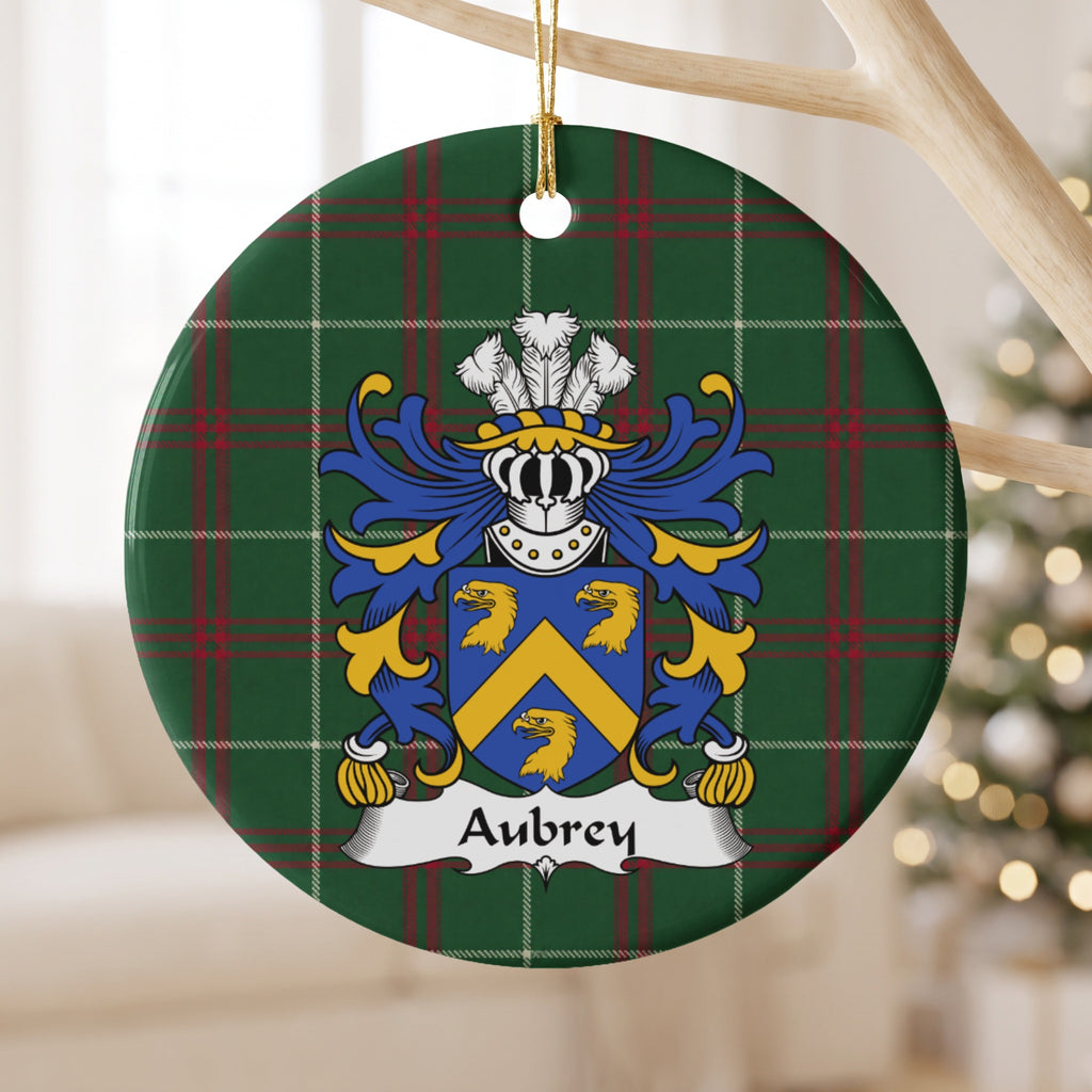 Aubrey ornament hanging from a pale branch; three gold eagle heads and a gold chevron on a blue shield on Welsh national tartan.