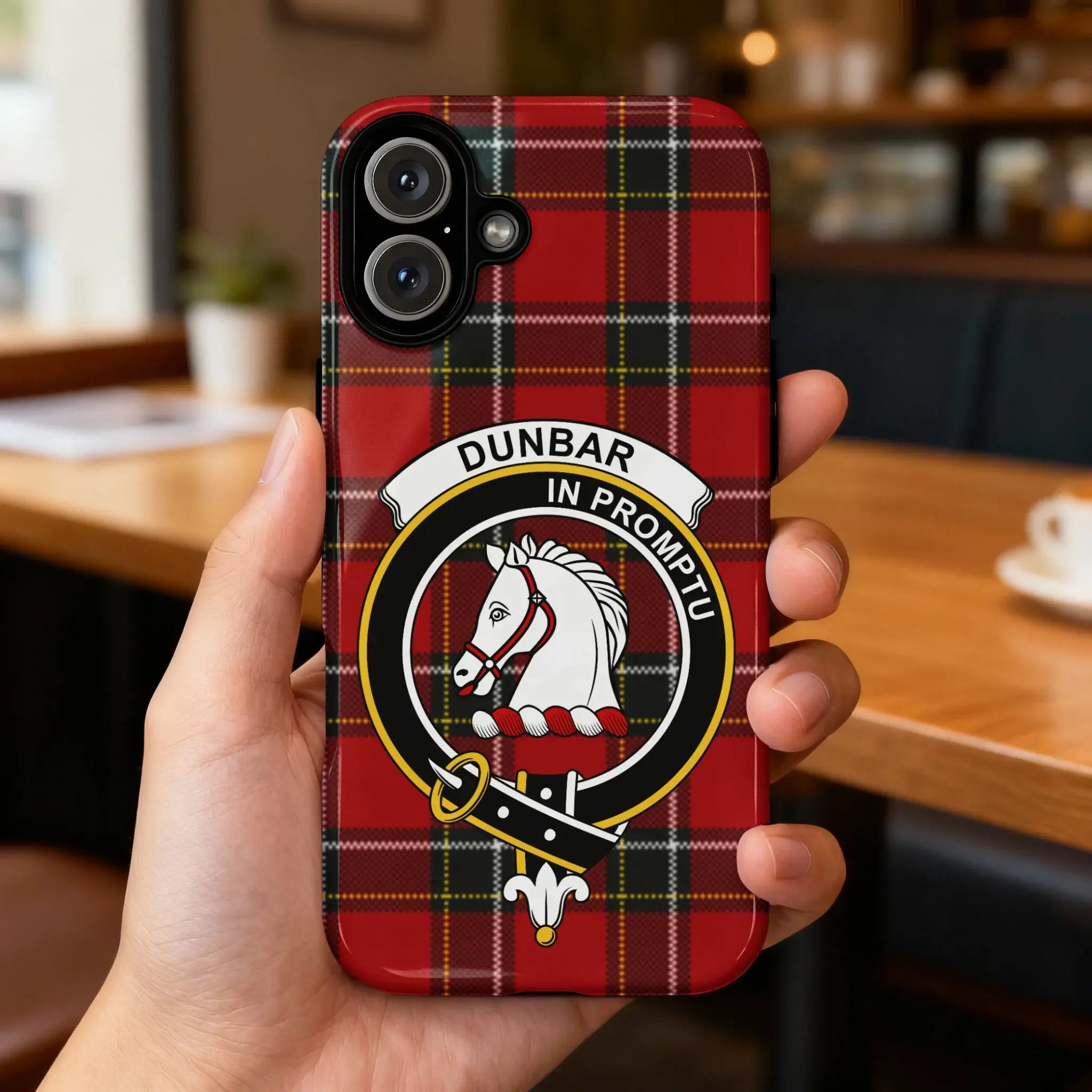 Clan Dunbar tartan case on phone — slim glossy finish, crest detail visible, angled view