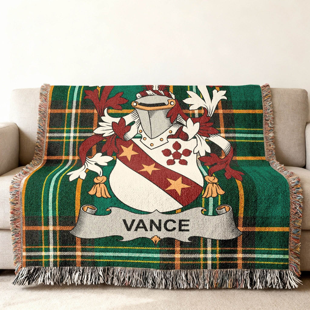 Green tartan blanket with Vance family crest draped over a sofa.