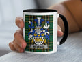 White mug with black handle featuring the McVeagh family crest on a plaid background.