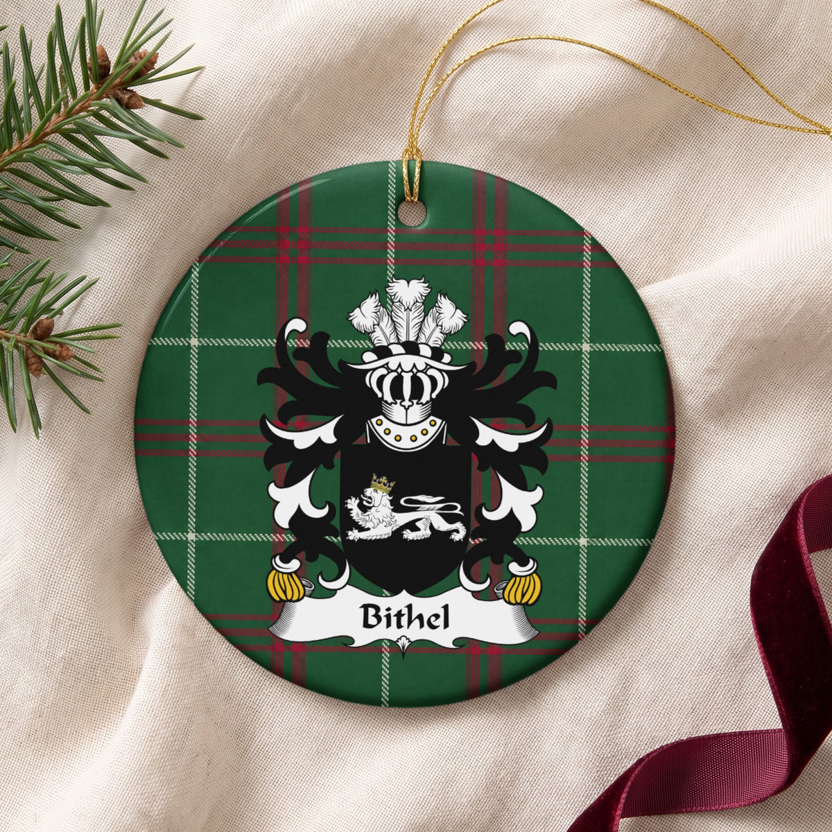 Bithel ornament on cream fabric with gold string, evergreen and burgundy ribbon; a white reclining lion with a gold crown on black on Welsh national tartan.