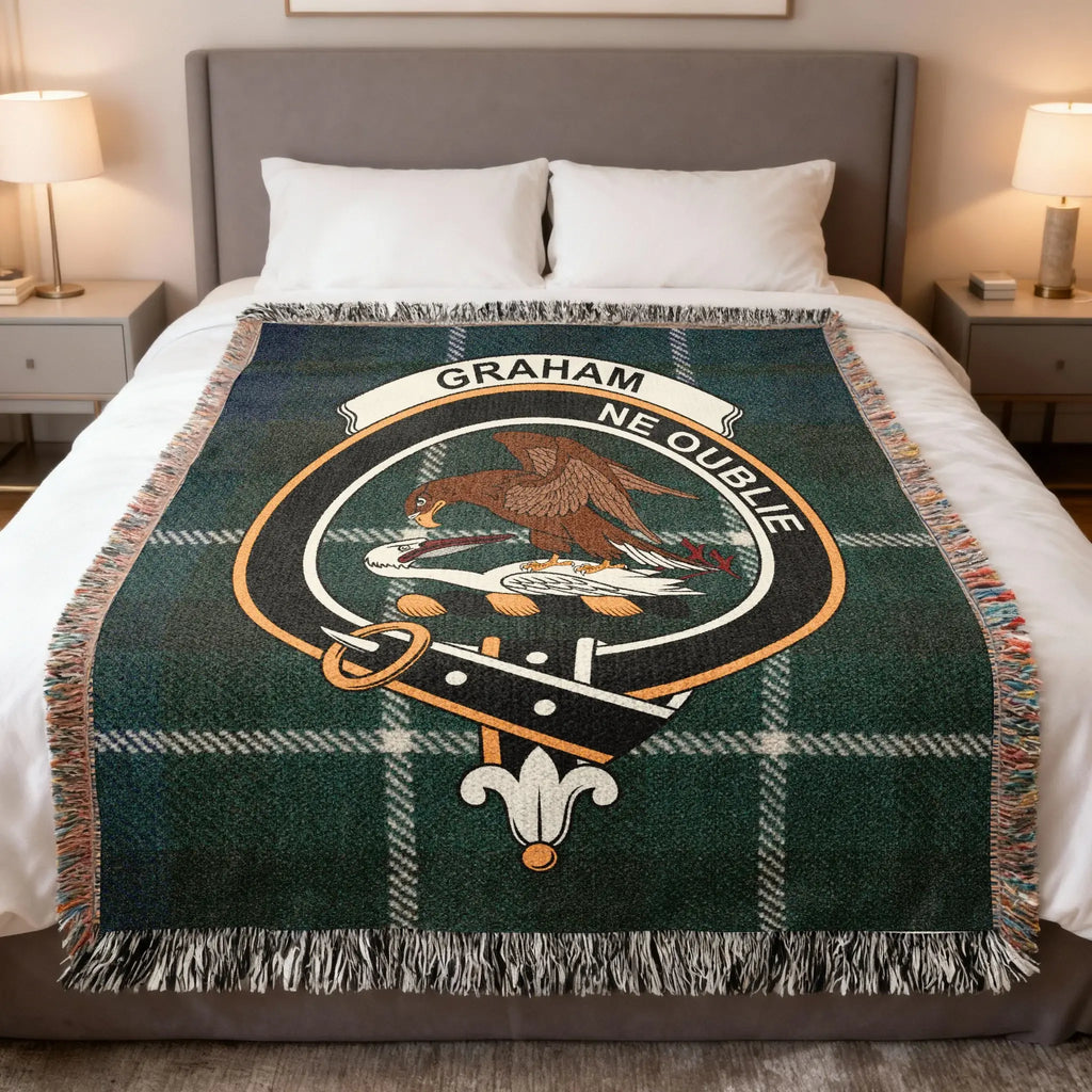 Clan Graham tartan woven cotton blanket — blue and green check with falcon crest, draped on sofa