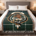 Clan Graham tartan woven cotton blanket — blue and green check with falcon crest, draped on sofa