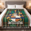 Green tartan throw blanket with Norreys family crest on a bed.