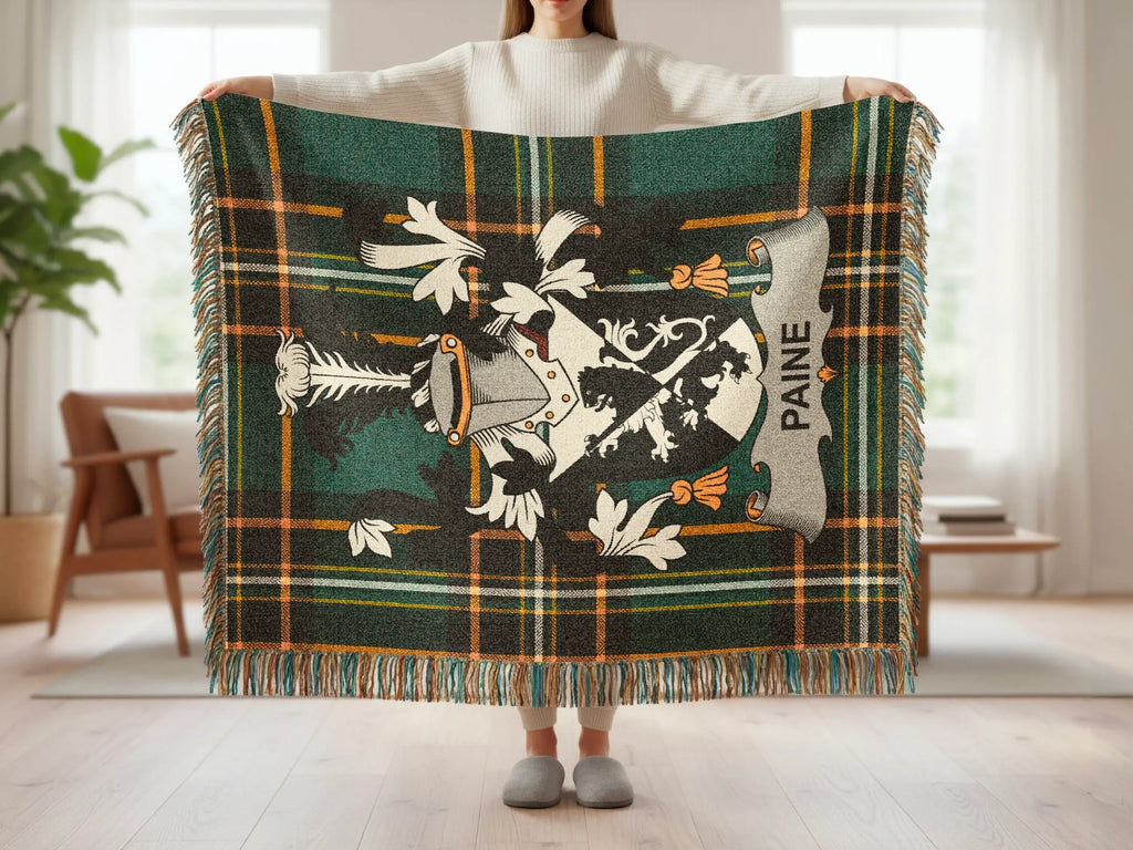 Green tartan blanket with white lion crest and "PAINE" text, held open by a person.