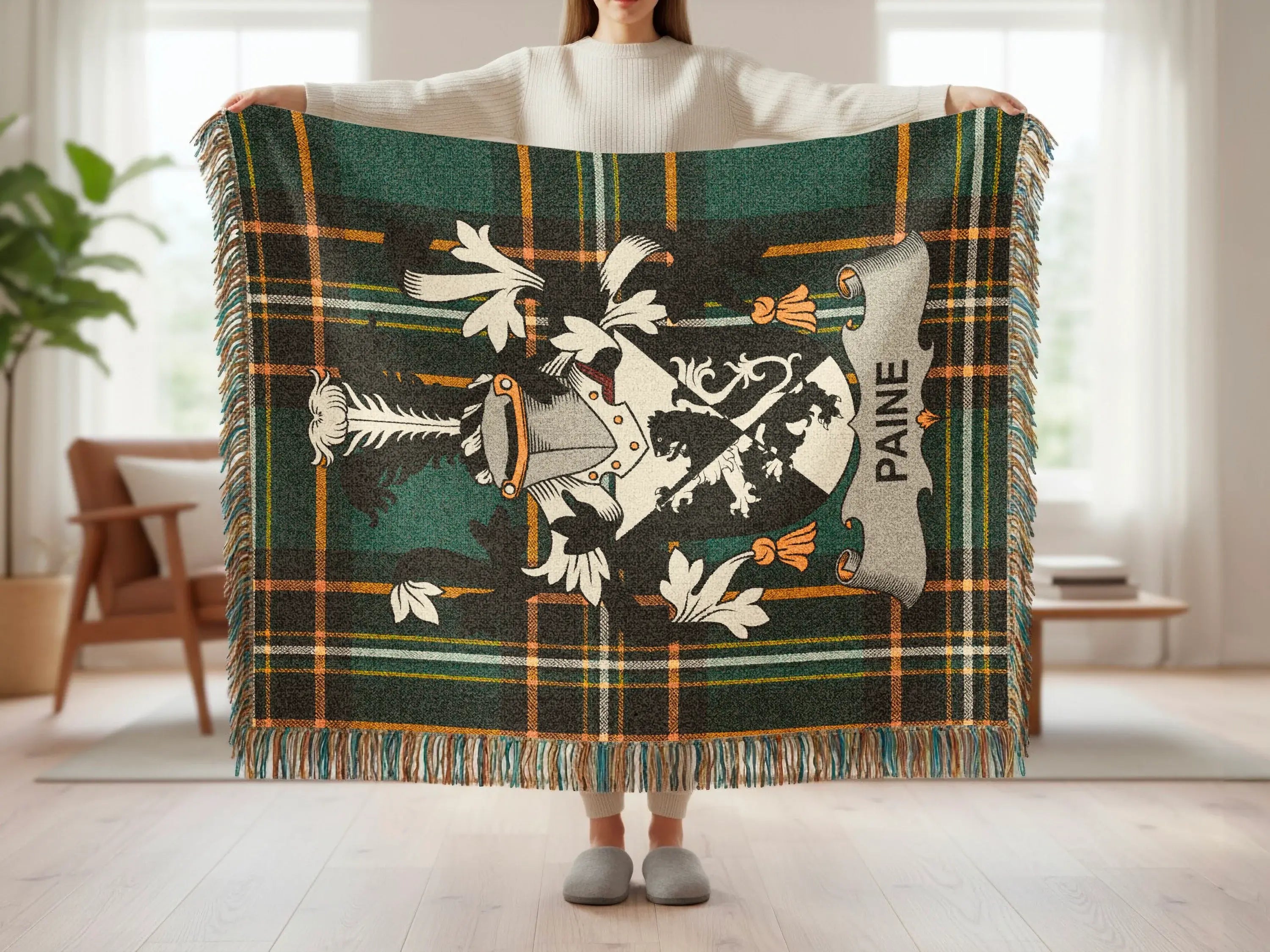 Green tartan blanket with white lion crest and "PAINE" text, held open by a person.