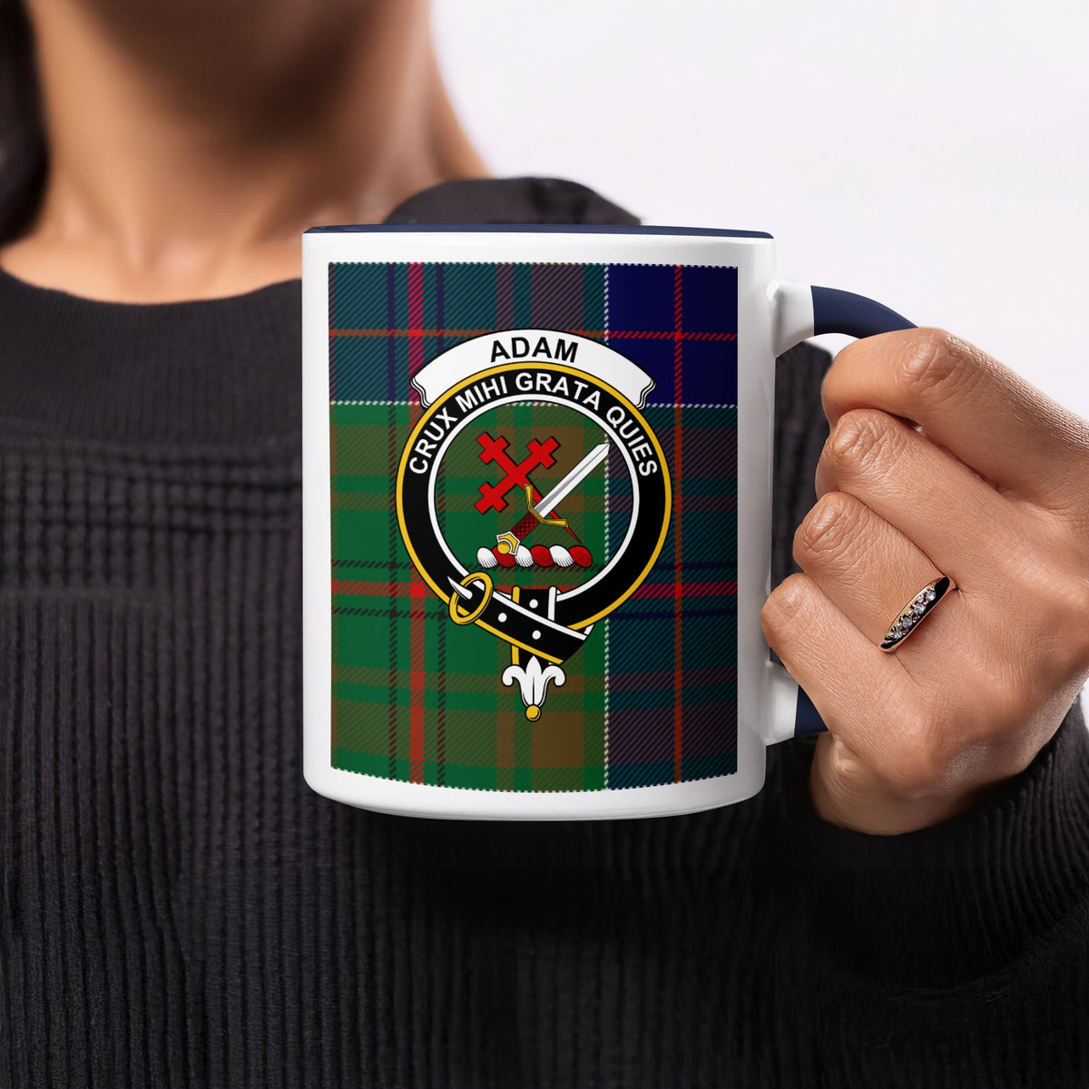 Close-up lifestyle view of Adam Scottish family crest artwork on a navy 11 oz accent mug with a tartan background