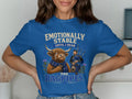 Blue t-shirt with a crying cow wearing a scarf and a bagpiper, text reads "Emotionally Stable Until I Hear The Bagpipes."