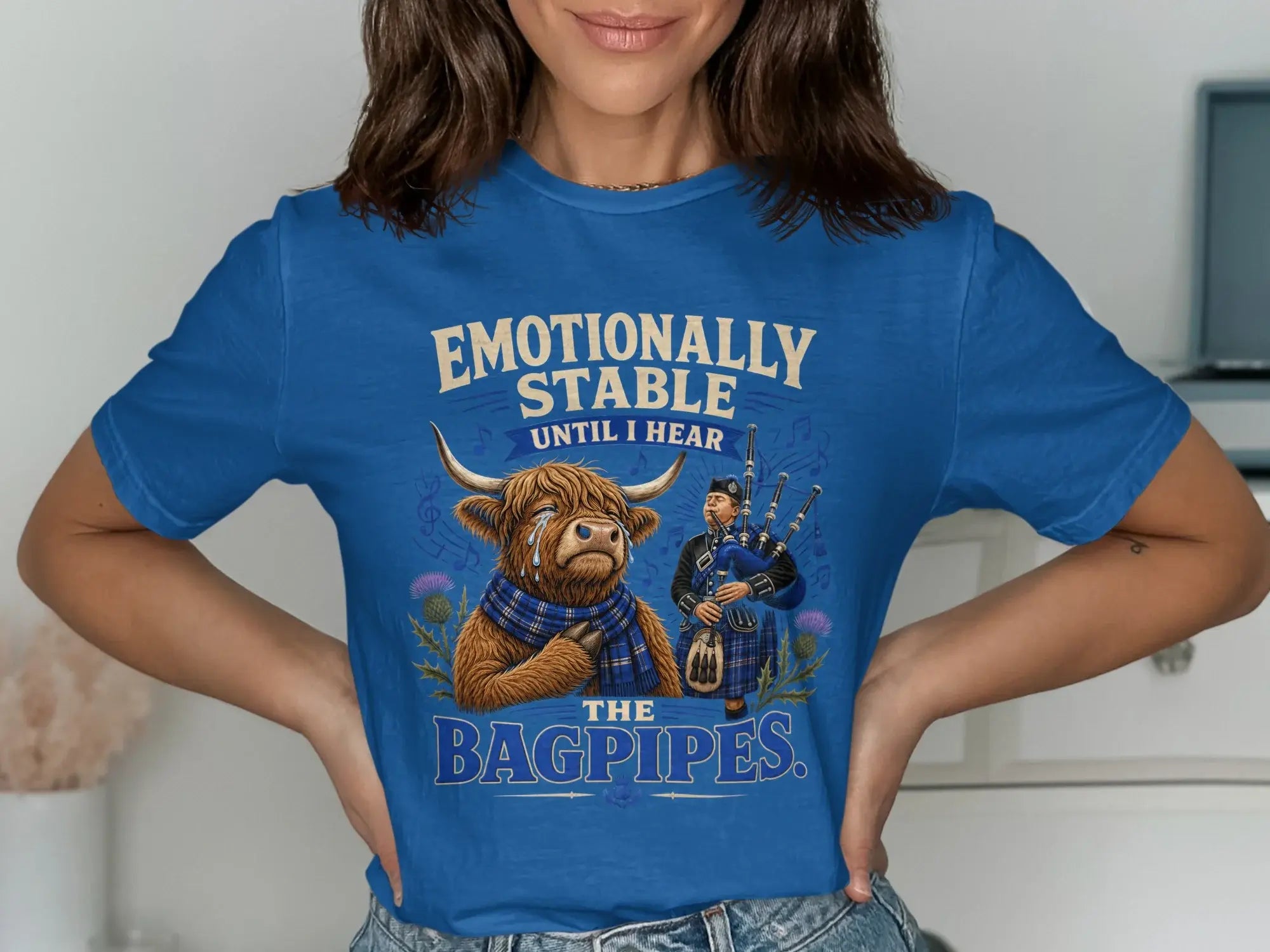 Blue t-shirt with a crying cow wearing a scarf and a bagpiper, text reads "Emotionally Stable Until I Hear The Bagpipes."