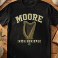 Moore Irish harp T-shirt in Black, with cream surname lettering, a gold-toned harp, green shamrock and “Irish Heritage” text.