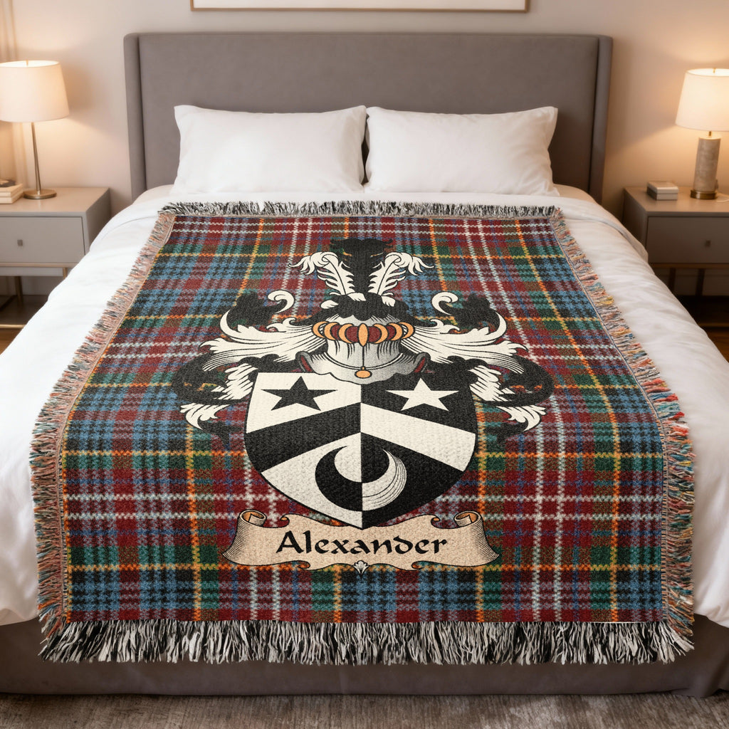 Alexander Scottish family crest woven blanket on a Caledonia tartan background, displayed on a bed