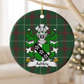 Ashley ornament hanging from a pale branch; a green-and-white shield crossed by a black band with three white flower-like motifs on Welsh national tartan.