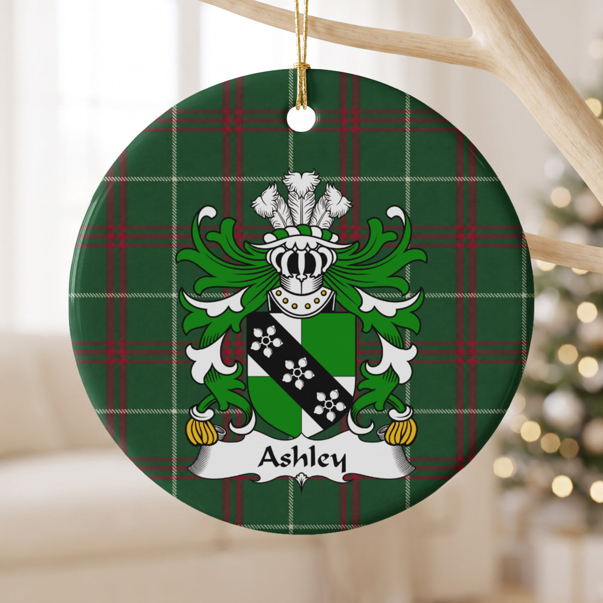 Ashley ornament hanging from a pale branch; a green-and-white shield crossed by a black band with three white flower-like motifs on Welsh national tartan.