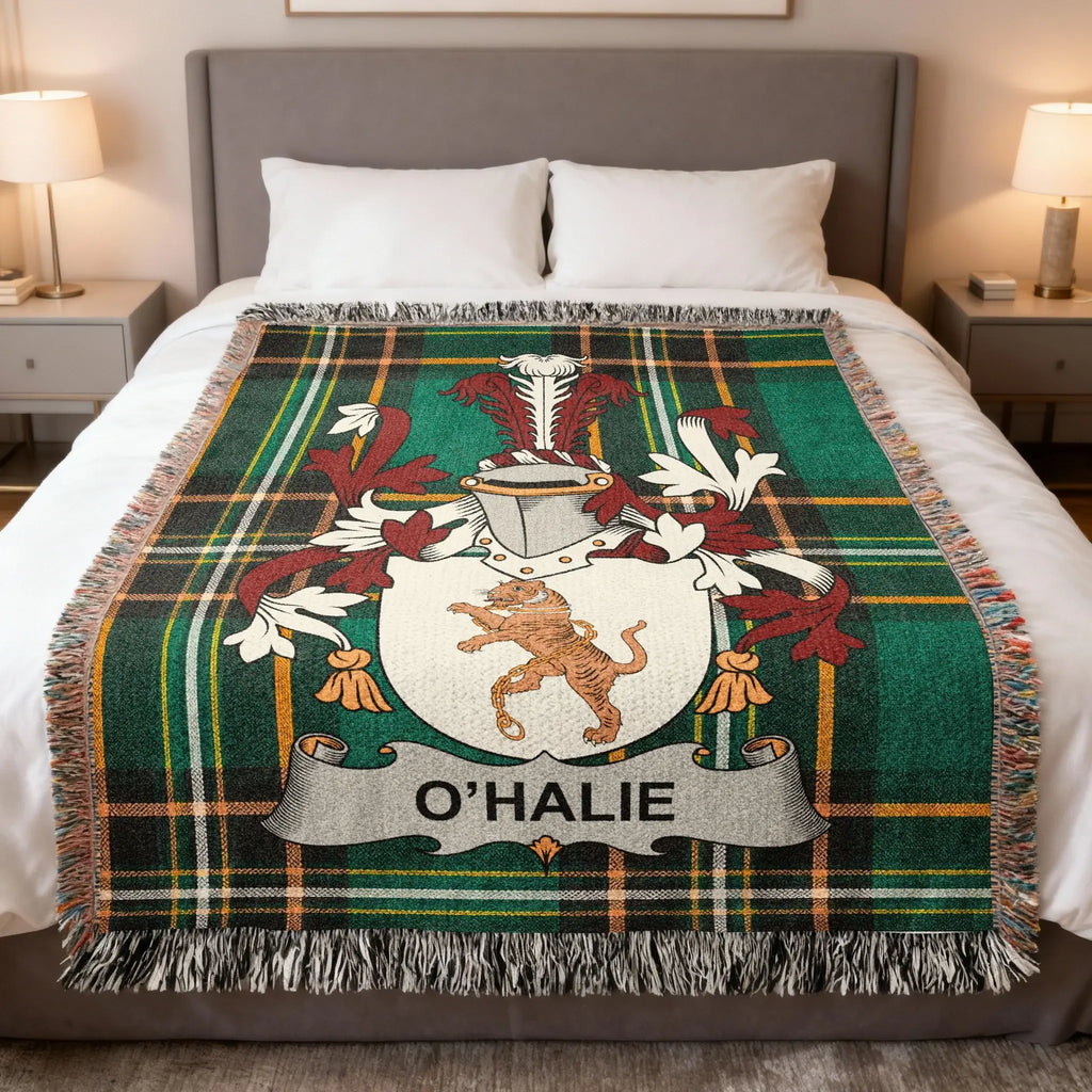 Tartan blanket with O'HALIE family crest on a bed.