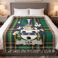 Tartan blanket with Lea family crest displayed on a bed.