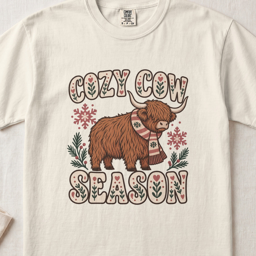 Cozy Cow Season Highland cow design on an Ivory Comfort Colors 1717 T-shirt, flat lay