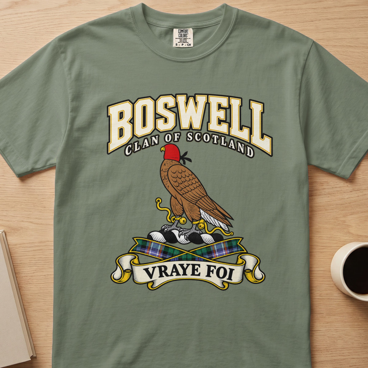 Boswell clan crest with hooded brown bird on a sage green Comfort Colors T-shirt, front view