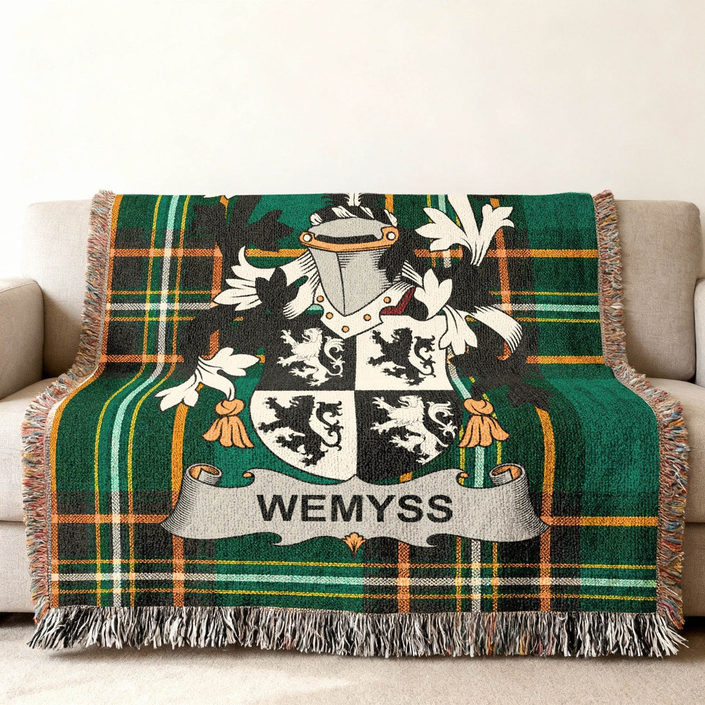 Wemyss tartan throw blanket with family crest on a sofa.