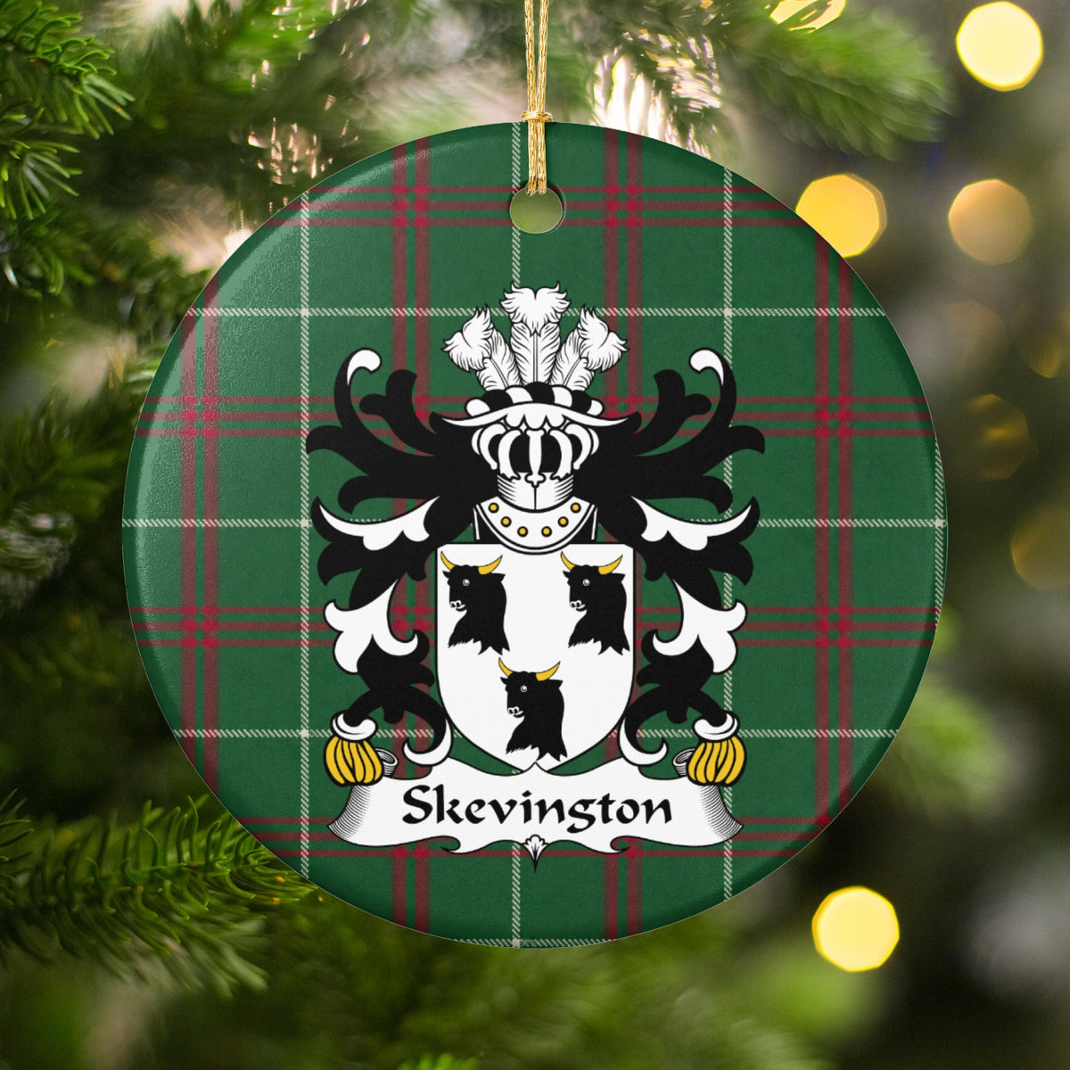 Skevington ornament hanging on a Christmas tree, with white shield with three black bull heads and gold horns on Welsh National Tartan.
