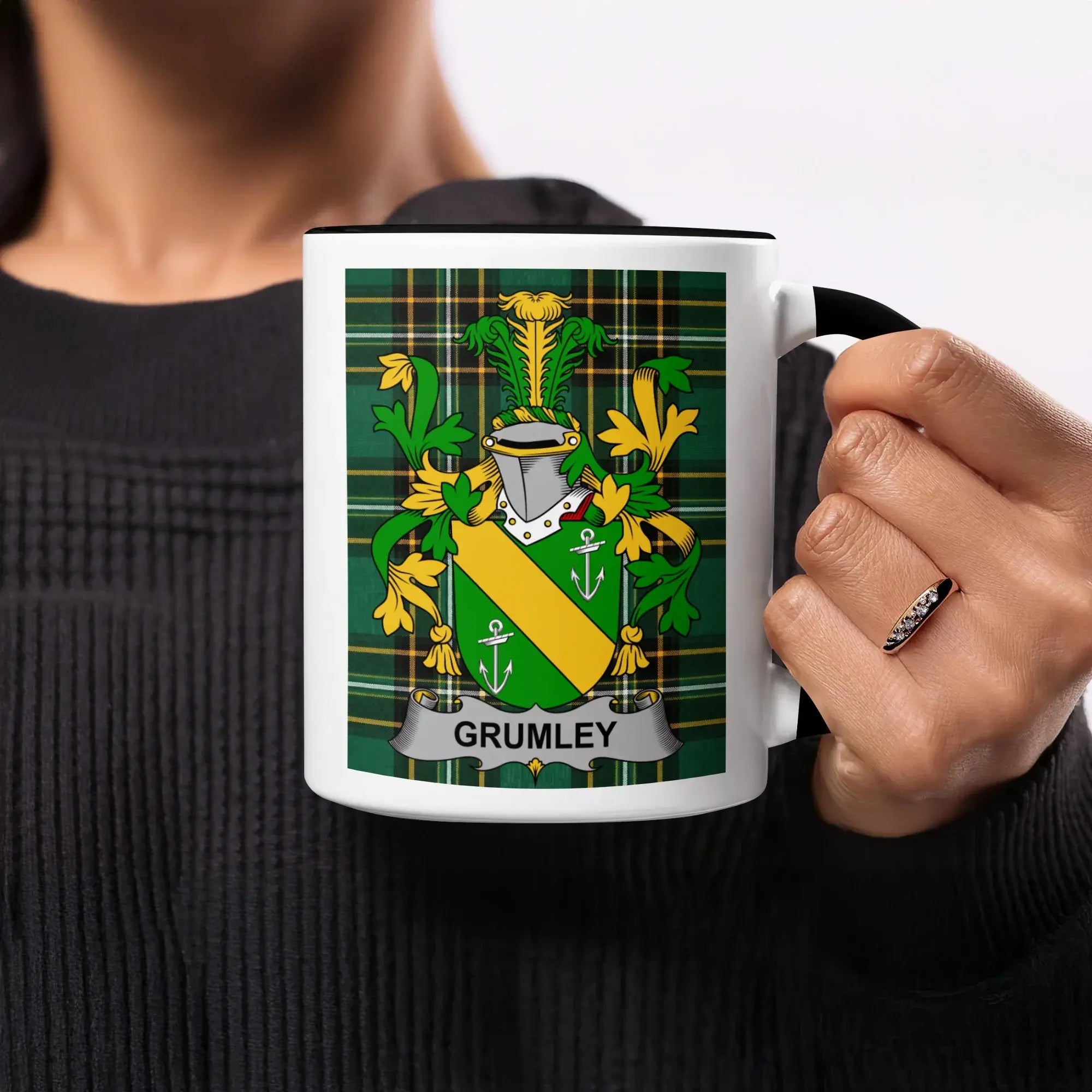 White mug with black rim featuring the Grumley family crest on a tartan background.
