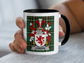 White mug with black rim featuring Condon coat of arms on green plaid background.