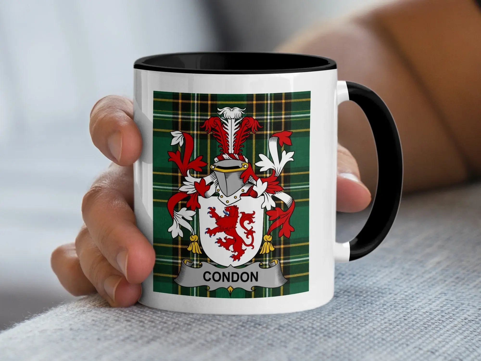 White mug with black rim featuring Condon coat of arms on green plaid background.