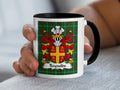 White mug with black handle featuring a green plaid background and the Reynolds coat of arms.