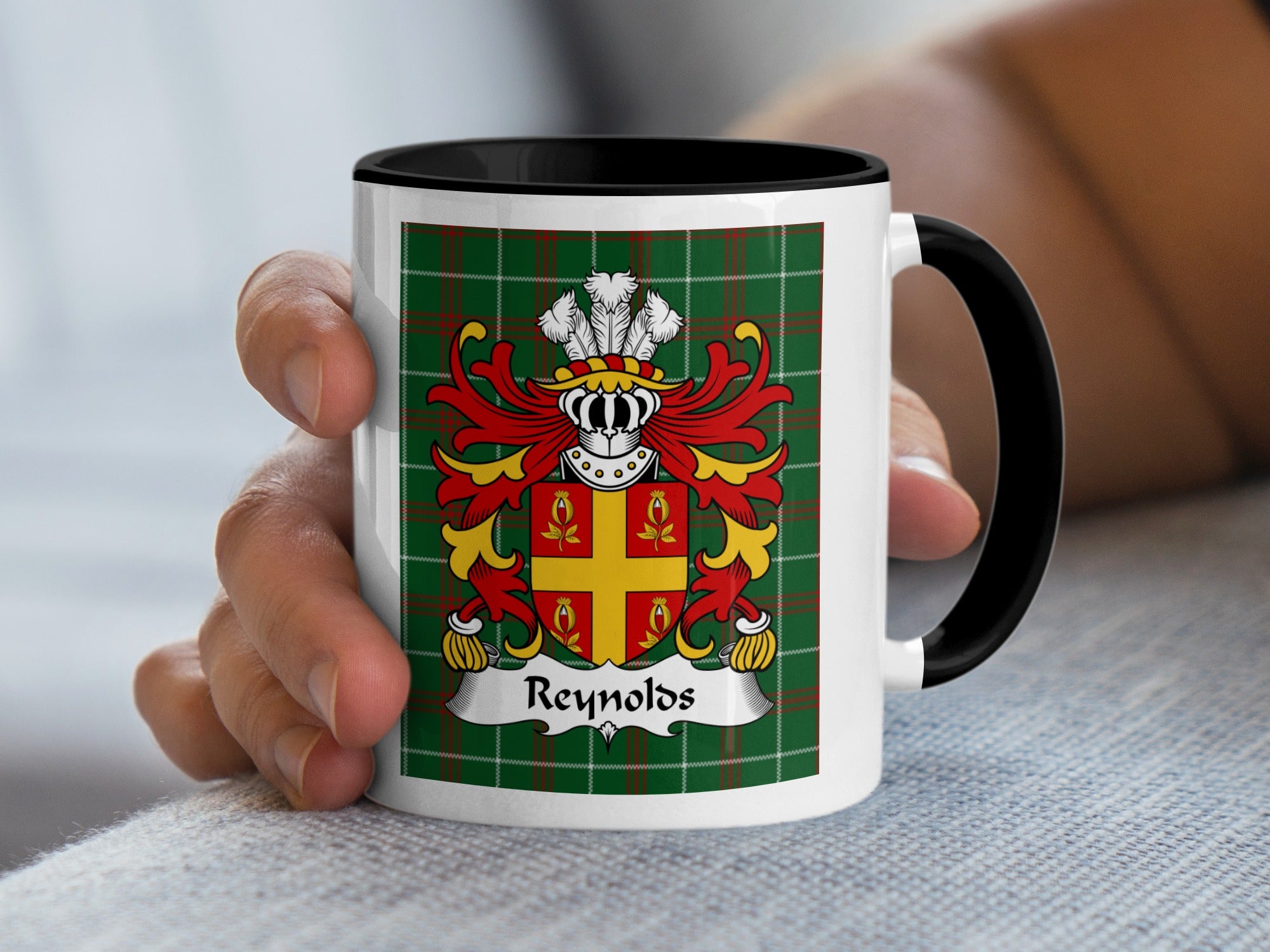 White mug with black handle featuring a green plaid background and the Reynolds coat of arms.