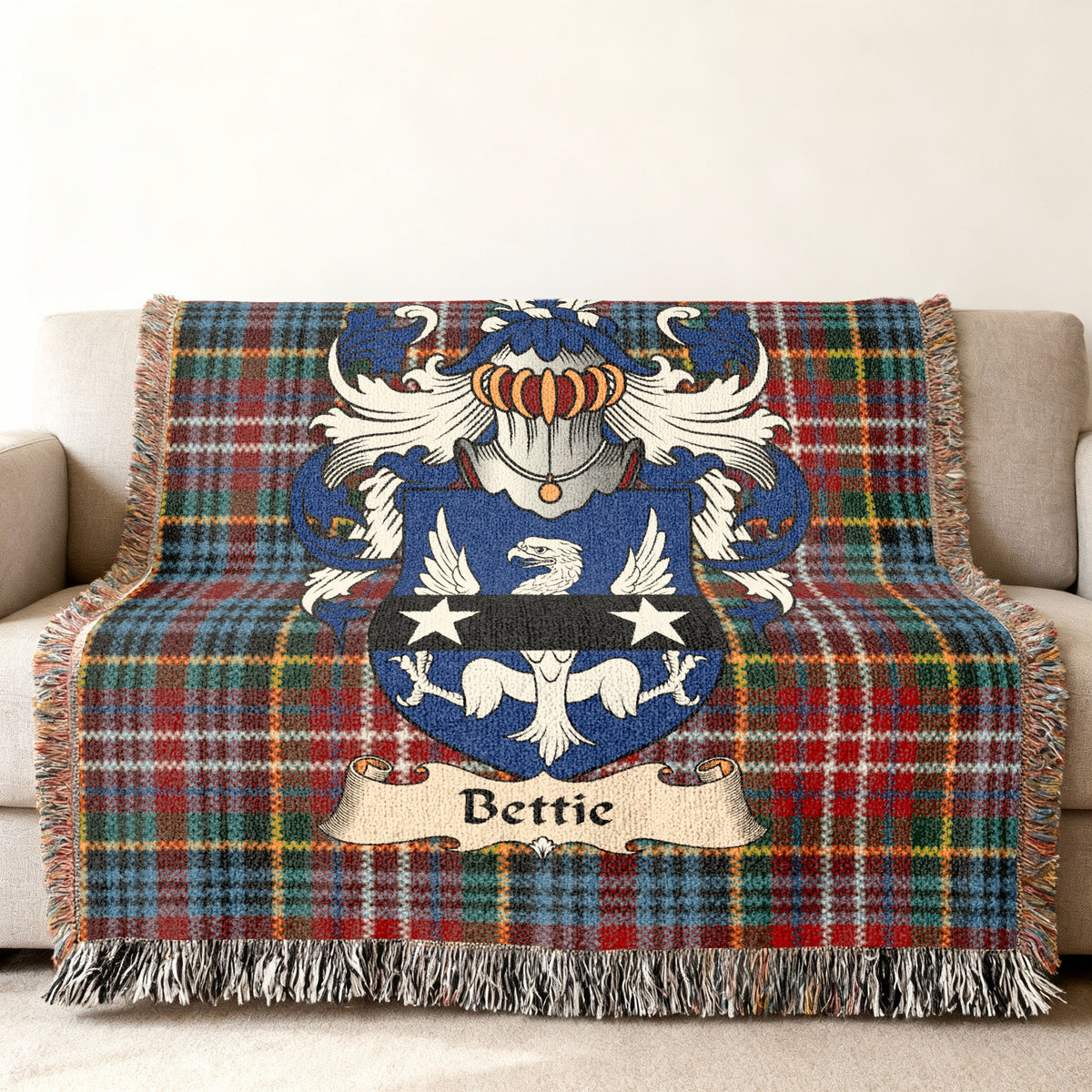 Bettie Scottish family shield woven blanket with Caledonia tartan background on a sofa