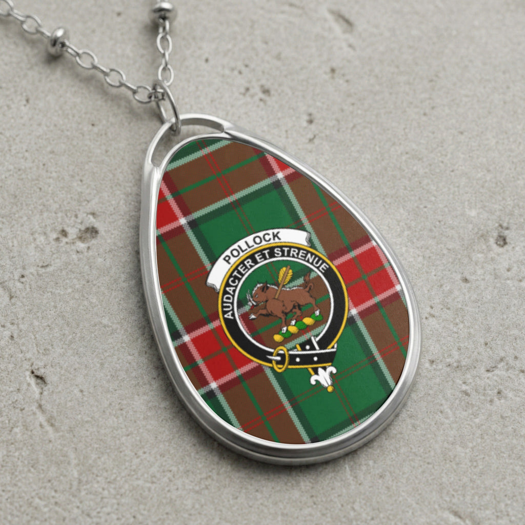 Oval pendant necklace with Pollock tartan and crest on a concrete surface.