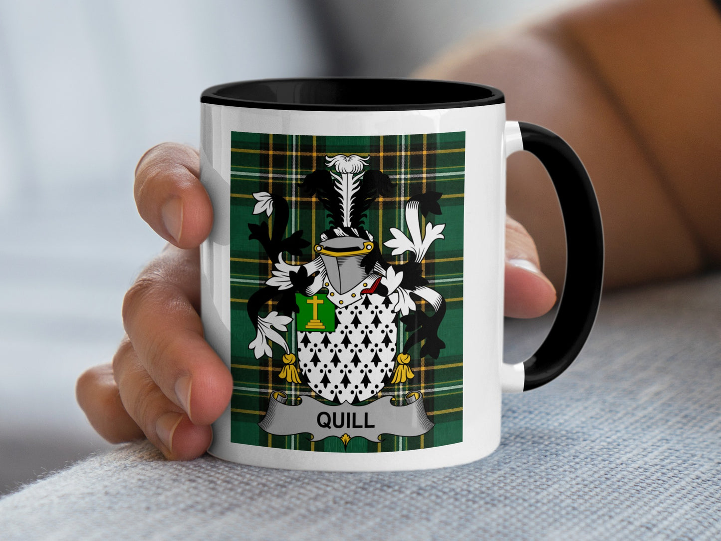 Mug with black handle, featuring a green plaid background and the "Quill" family crest.