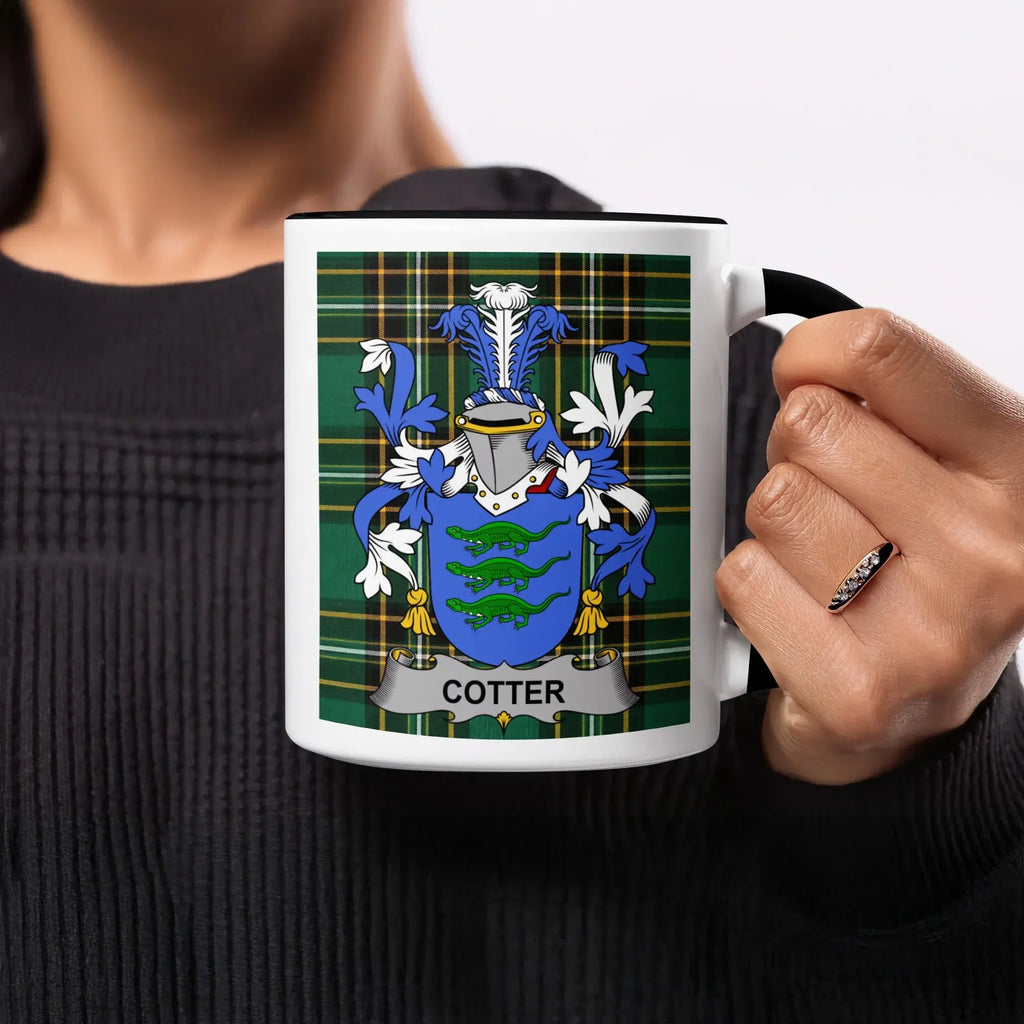 Cotter family crest on a black and white mug, held by a person.