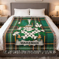 Wakeman family crest on a green tartan plaid blanket draped on a bed.