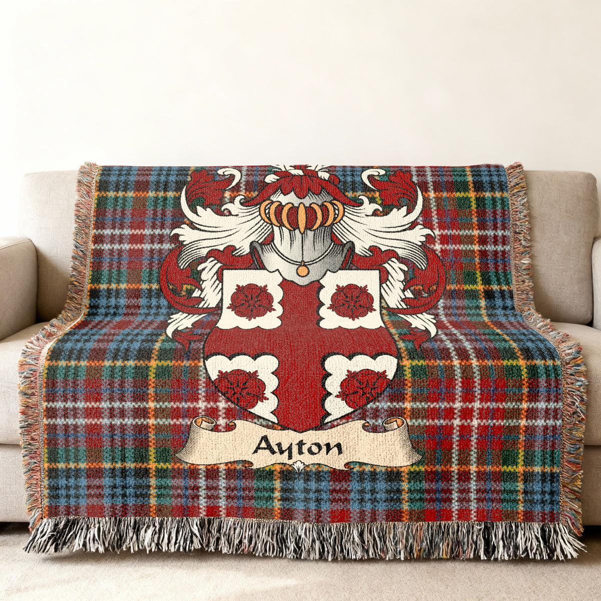 Ayton Scottish family shield woven blanket with Caledonia tartan background on a sofa