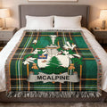 McAlpine tartan blanket with coat of arms centered on a bed.