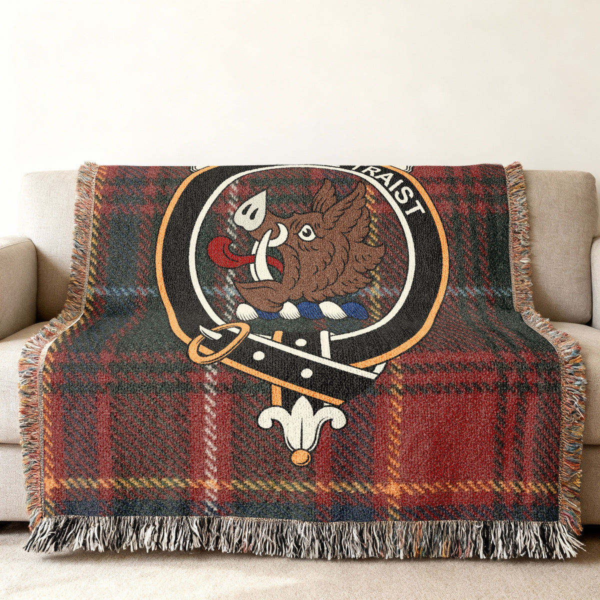 Close view of the Innes woven blanket draped over a sofa, showing the crest and fringed edges