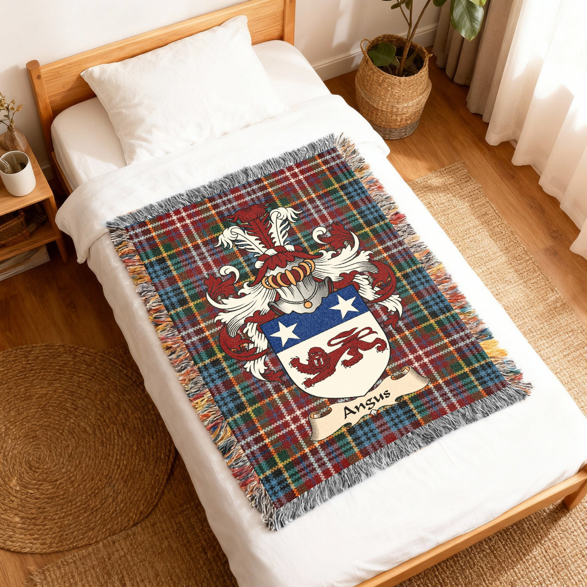Angus Scottish family shield woven blanket with Caledonia tartan background, displayed on a bed