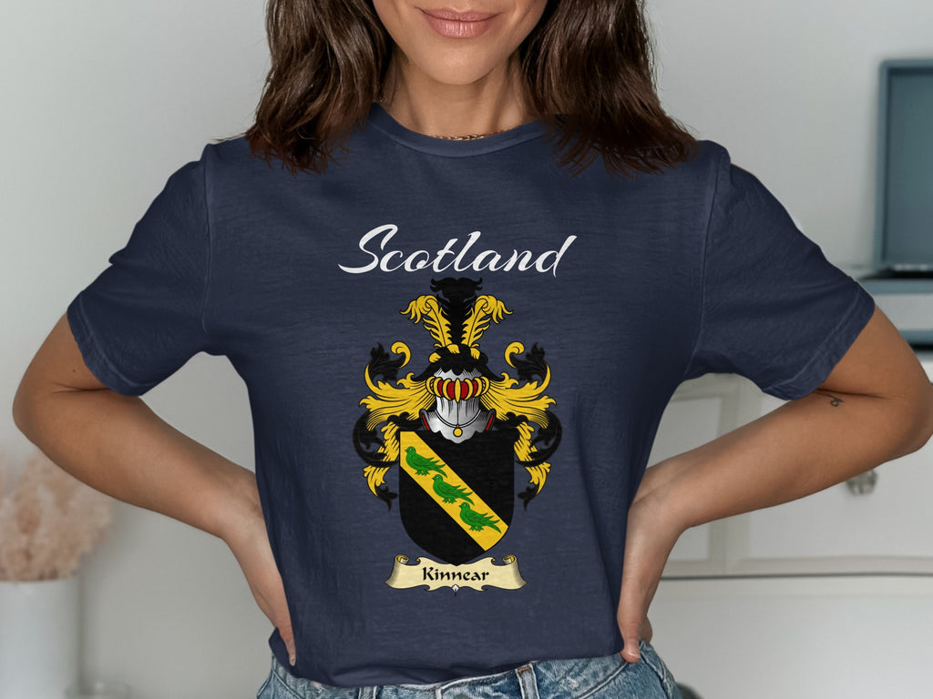 Model wearing a navy Kinnear T-shirt featuring a gold diagonal band with green leaves on black