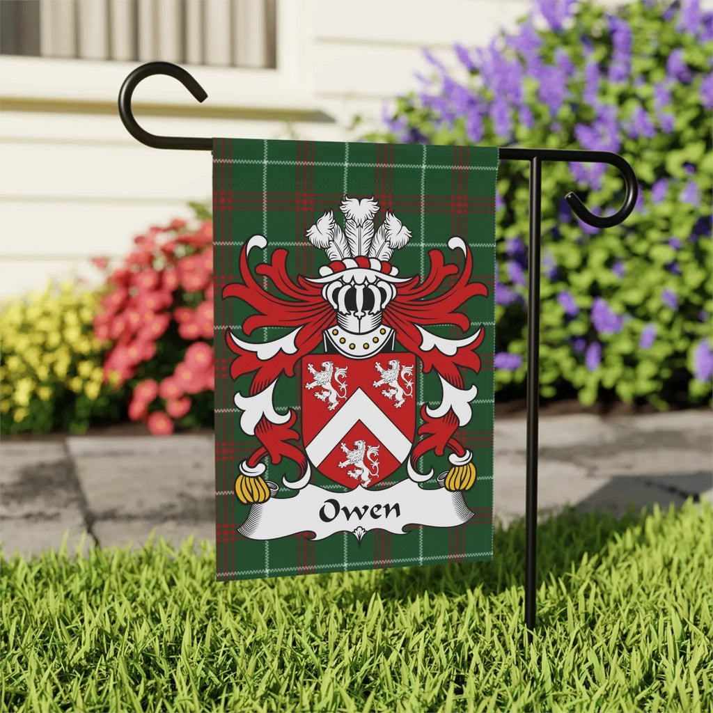 Green tartan flag with white Owen family crest, displayed outdoors.