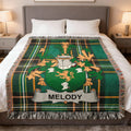 Tartan blanket with Melody coat of arms draped on a bed.