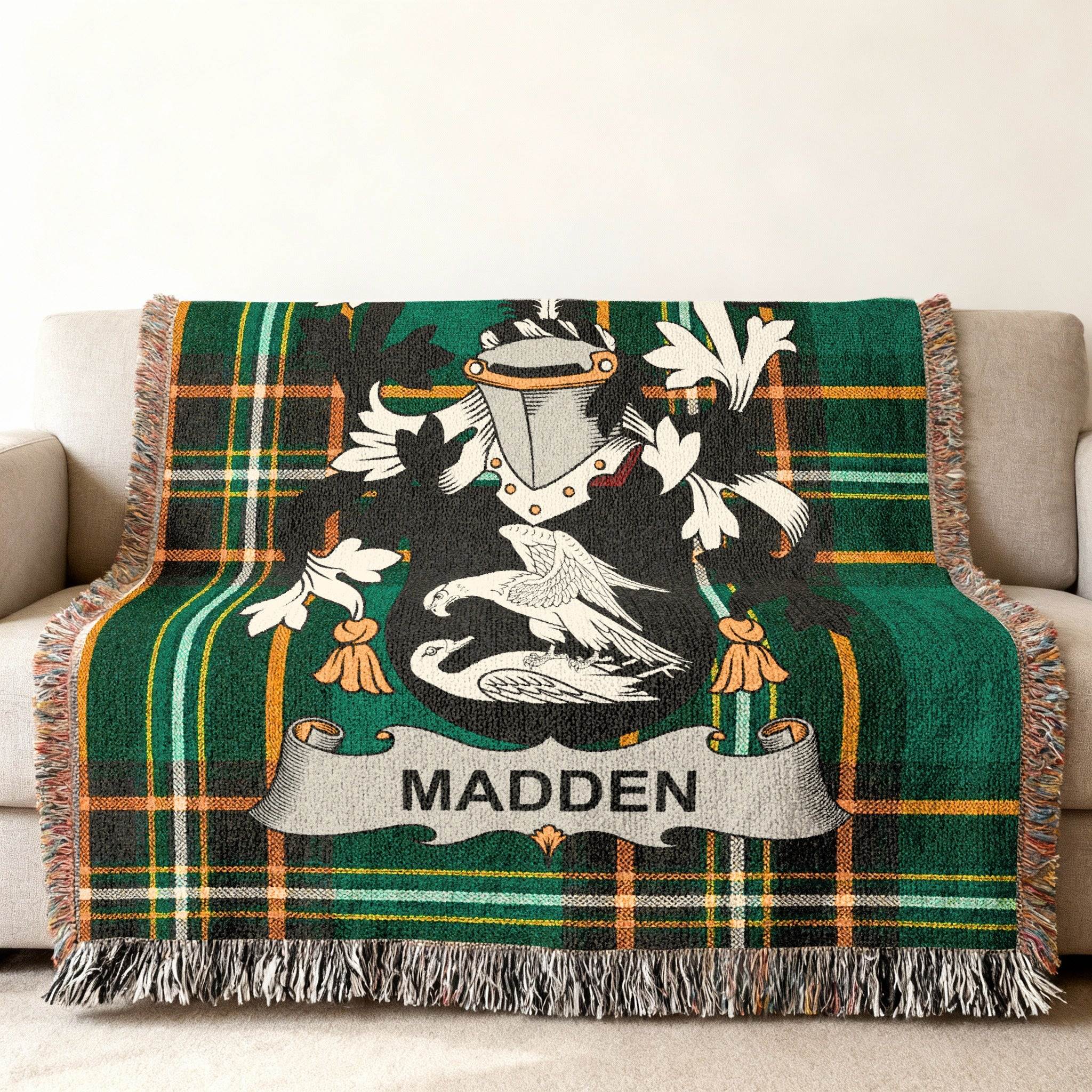 Green tartan throw blanket with Madden family crest centered on a sofa.